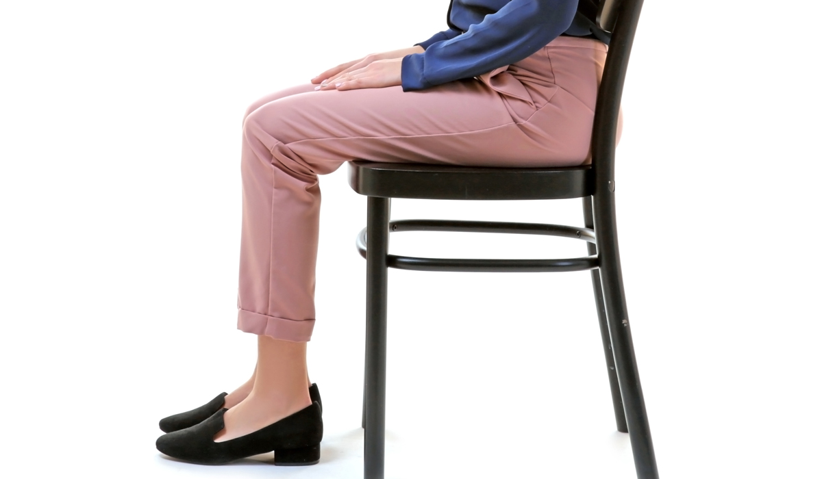 Brightly-Biomarkers-incorrect-posture-concept-young-woman-sitting-chair-against-white-background