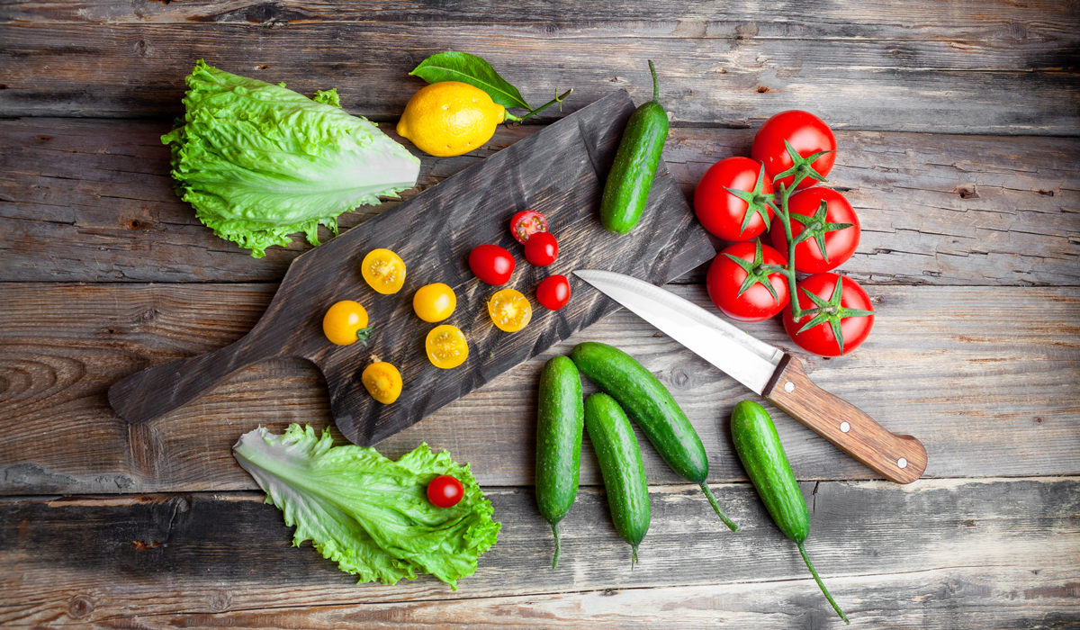 Brightly-Biomarkers-set-tomatoes-lettuce-lemon-knife-cucumber-cutting-board-dark-wooden-background-top-view